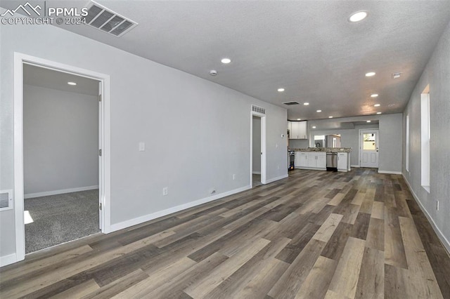 unfurnished living room featuring dark wood-type flooring and a textured ceiling