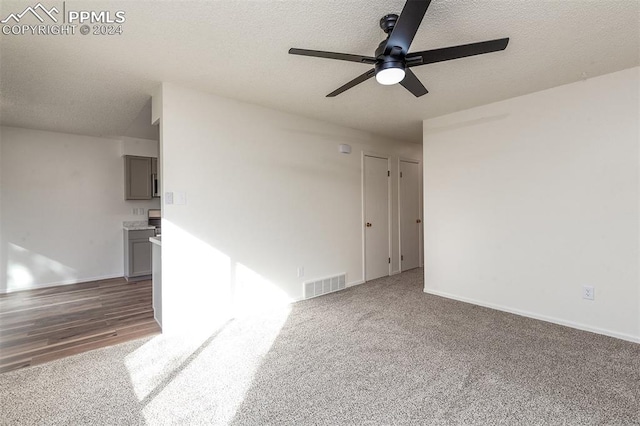 empty room featuring ceiling fan, a textured ceiling, and dark hardwood / wood-style flooring