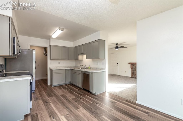 kitchen with gray cabinetry, a textured ceiling, ceiling fan, stainless steel appliances, and dark hardwood / wood-style floors