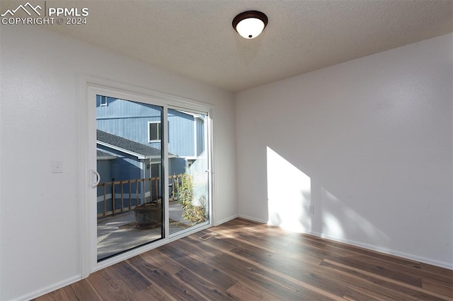 spare room with a textured ceiling and dark hardwood / wood-style floors