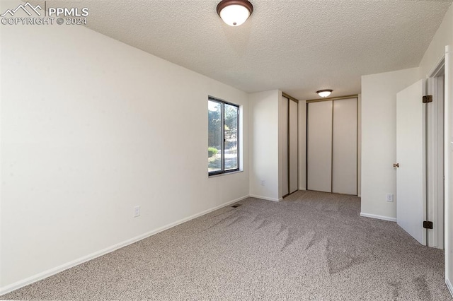 unfurnished bedroom with a textured ceiling and carpet floors