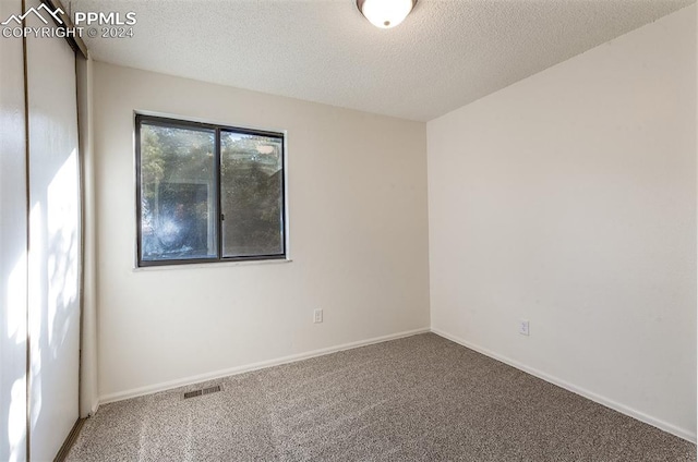 carpeted empty room featuring a textured ceiling