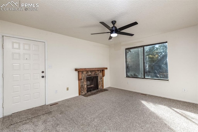 unfurnished living room with a textured ceiling, a fireplace, carpet flooring, and ceiling fan