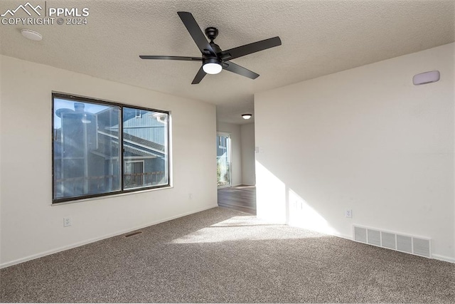 carpeted empty room featuring ceiling fan and a textured ceiling