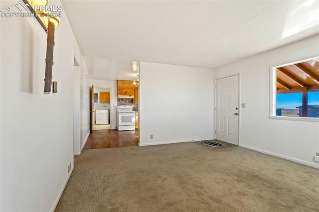 unfurnished living room featuring dark carpet and washer / clothes dryer