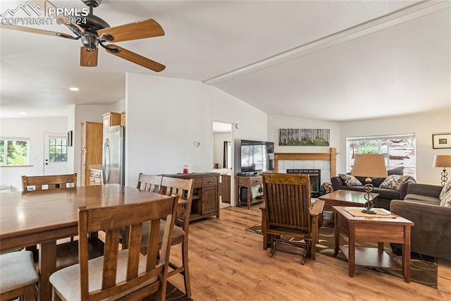 dining area with ceiling fan, vaulted ceiling, light wood-type flooring, and a fireplace