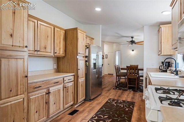 kitchen with hardwood / wood-style floors, ceiling fan, stainless steel fridge with ice dispenser, sink, and white gas range oven