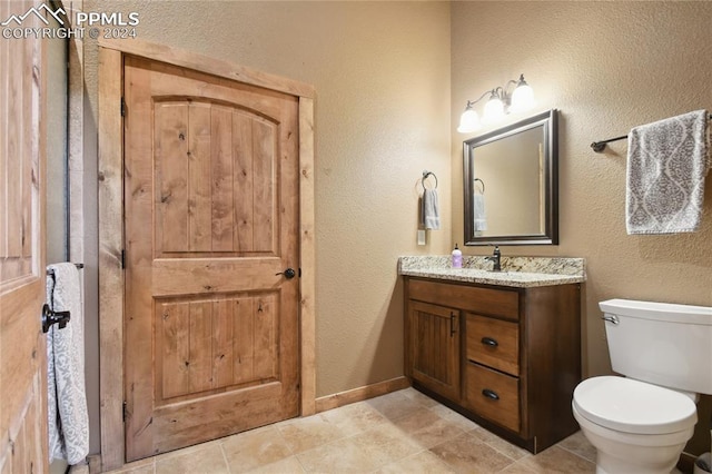 bathroom with toilet, vanity, and tile patterned flooring