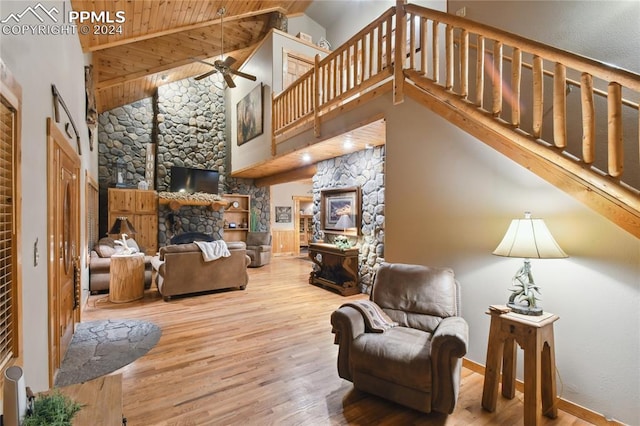 living room with a stone fireplace, wood-type flooring, wooden ceiling, high vaulted ceiling, and ceiling fan