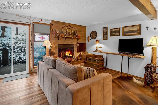 living room with wooden walls, wood-type flooring, and a textured ceiling