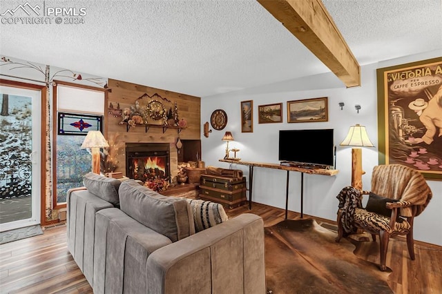 living room with a textured ceiling, hardwood / wood-style floors, wooden walls, and beamed ceiling