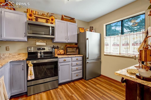 kitchen featuring gray cabinetry, appliances with stainless steel finishes, light hardwood / wood-style floors, and white cabinets