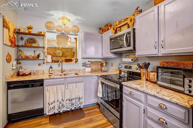 kitchen featuring light hardwood / wood-style flooring, sink, light stone counters, and stainless steel appliances