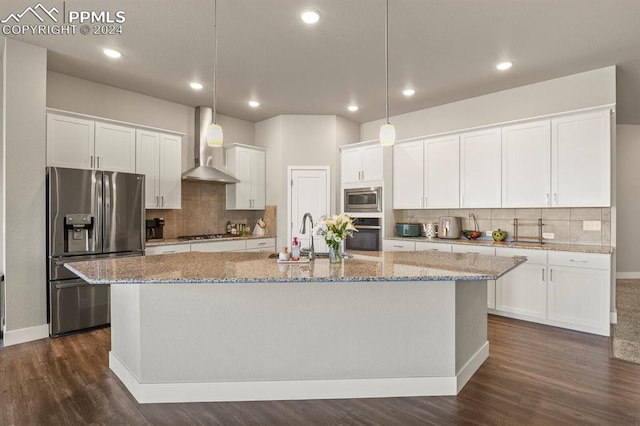 kitchen with an island with sink, stainless steel appliances, wall chimney exhaust hood, white cabinets, and dark hardwood / wood-style floors