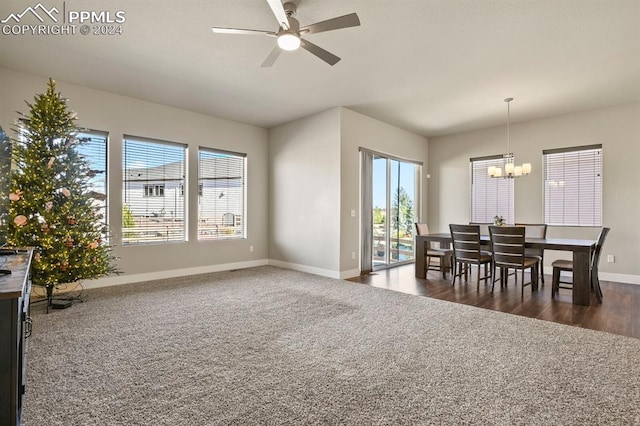 dining area with ceiling fan with notable chandelier, plenty of natural light, and dark hardwood / wood-style floors