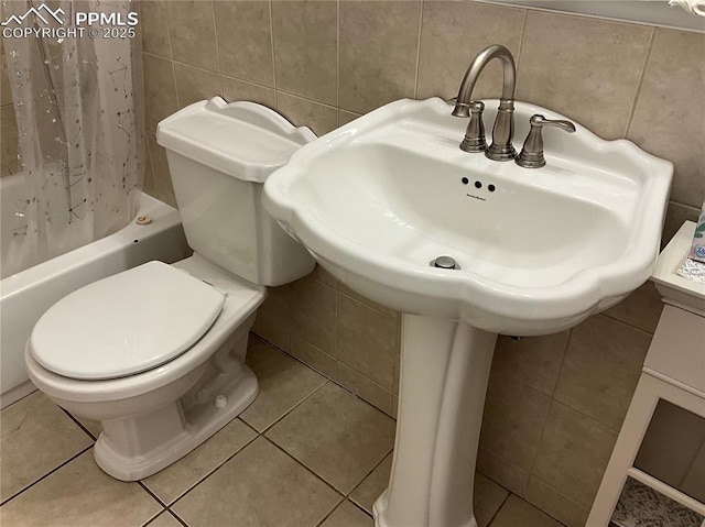 bathroom with tile patterned floors, shower / bath combo with shower curtain, tile walls, and toilet