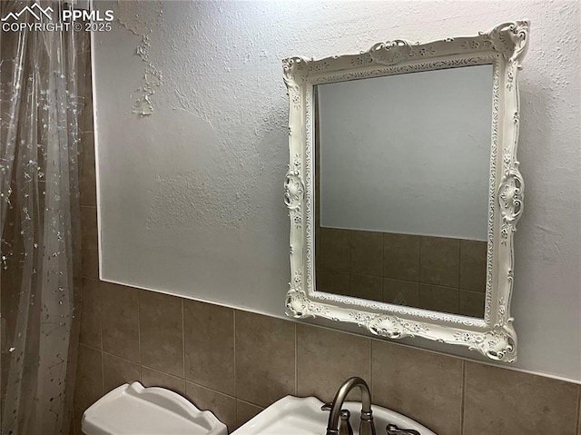 bathroom featuring sink and tile walls