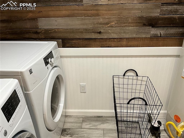 laundry room with wooden walls and washing machine and clothes dryer