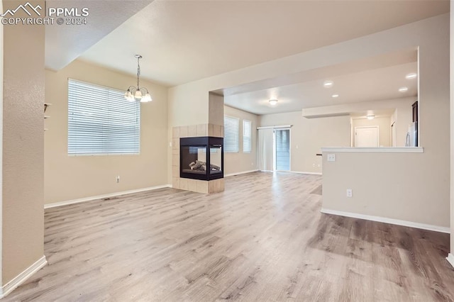 unfurnished living room with an inviting chandelier, hardwood / wood-style floors, and a fireplace