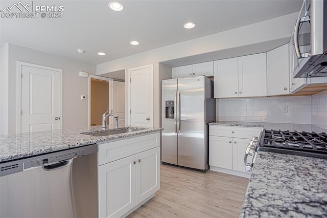 kitchen with sink, white cabinetry, light hardwood / wood-style flooring, and stainless steel appliances