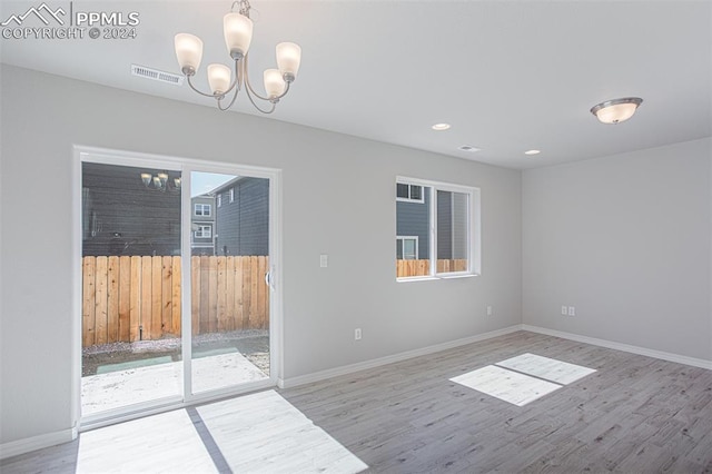 spare room with hardwood / wood-style flooring and a chandelier