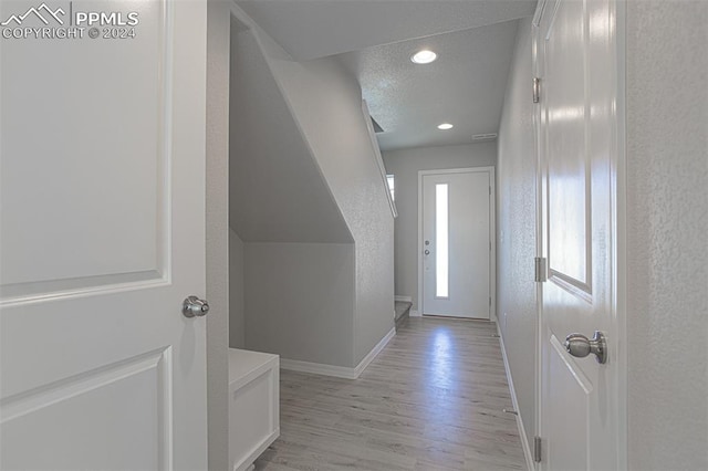 doorway with a textured ceiling and light wood-type flooring