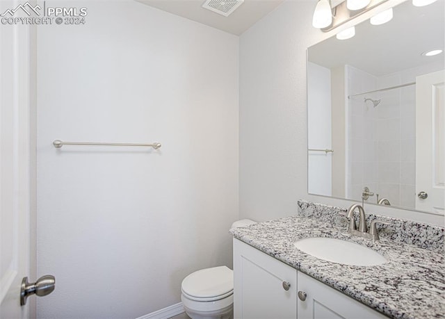 bathroom featuring vanity, a tile shower, and toilet