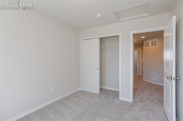 unfurnished bedroom with a closet and light colored carpet