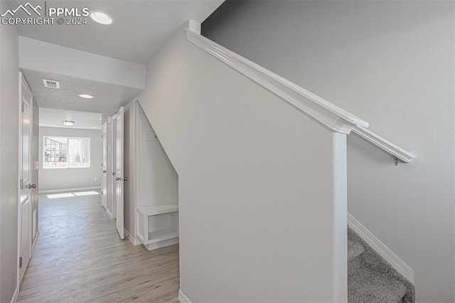 hall with light hardwood / wood-style flooring and a textured ceiling