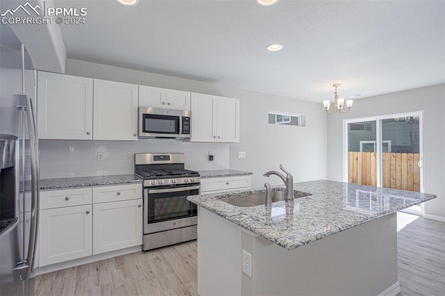 kitchen with white cabinets, tasteful backsplash, a center island with sink, sink, and stainless steel appliances