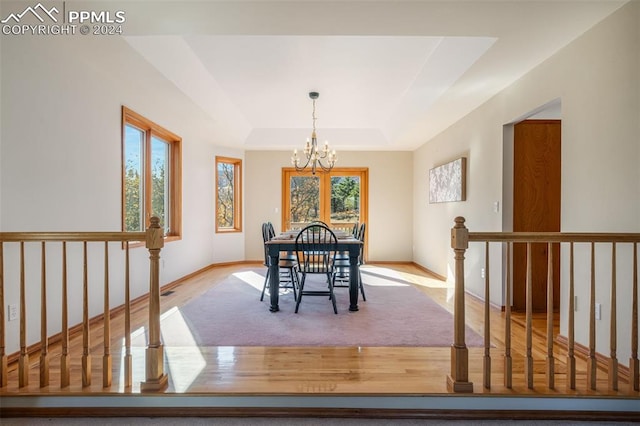 dining room with light hardwood / wood-style flooring, a raised ceiling, and an inviting chandelier