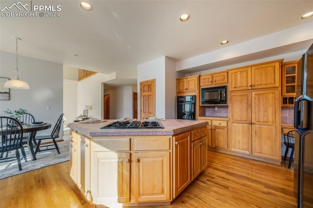 kitchen with tile countertops, black appliances, a kitchen island, and hanging light fixtures