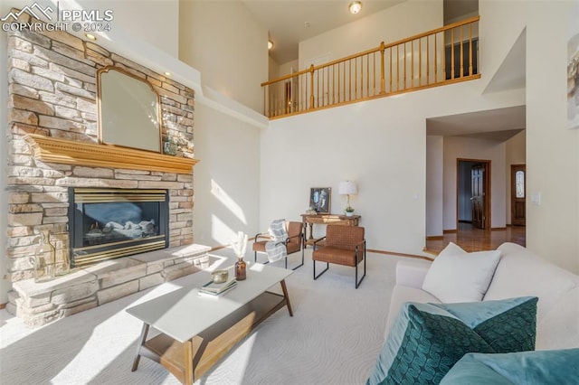 living room with a towering ceiling, a stone fireplace, and wood-type flooring