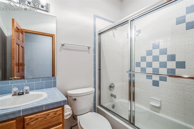 full bathroom with vanity, combined bath / shower with glass door, and toilet