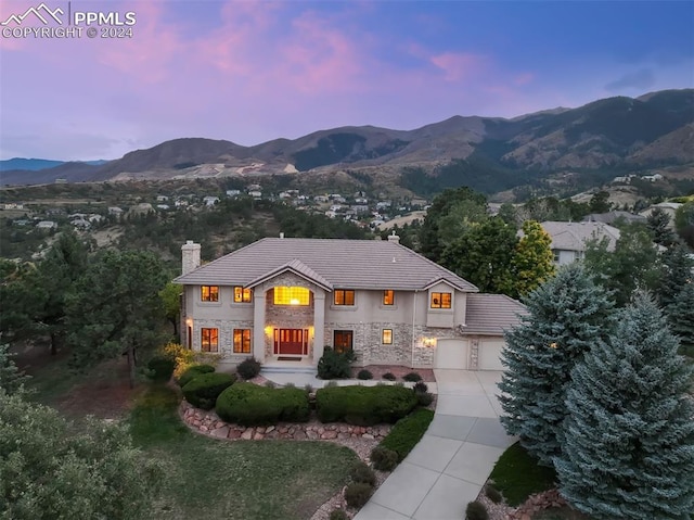 back house at dusk with a garage and a mountain view