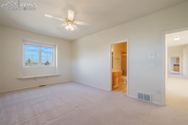 unfurnished bedroom with ensuite bathroom, light carpet, and ceiling fan