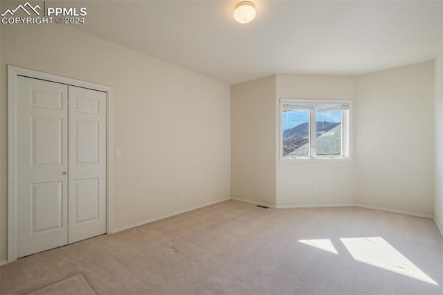 unfurnished bedroom featuring light colored carpet and a closet