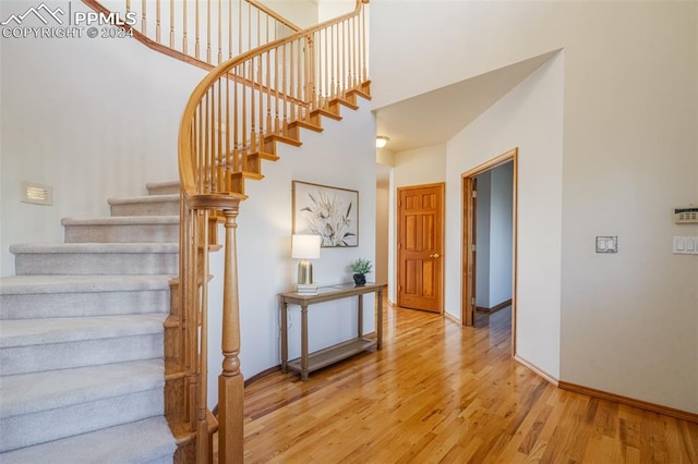 staircase with hardwood / wood-style floors and a towering ceiling