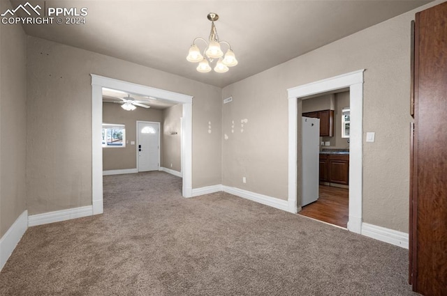 spare room featuring carpet flooring and ceiling fan with notable chandelier