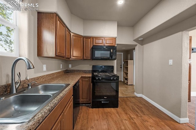 kitchen with sink, black appliances, and light wood-type flooring