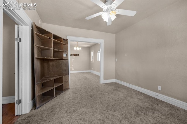 carpeted empty room featuring ceiling fan with notable chandelier