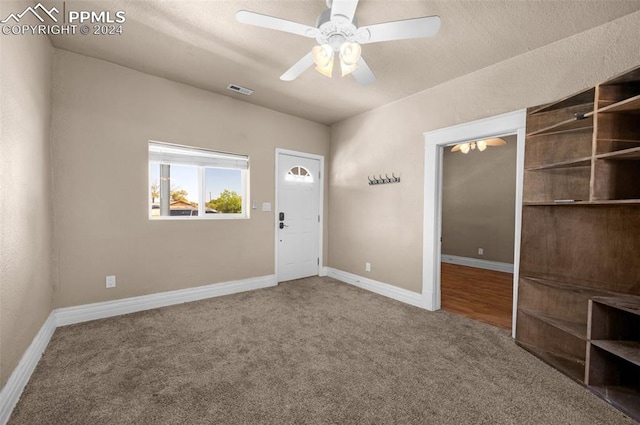 carpeted empty room featuring a textured ceiling and ceiling fan