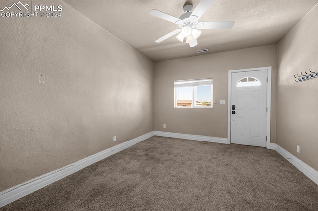 carpeted entrance foyer with a textured ceiling and ceiling fan