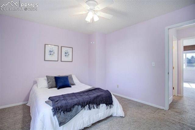 bedroom featuring light carpet, a textured ceiling, and ceiling fan