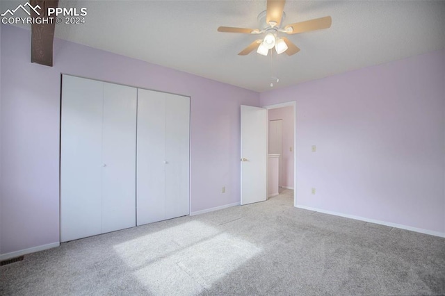 unfurnished bedroom featuring light carpet, a closet, and ceiling fan