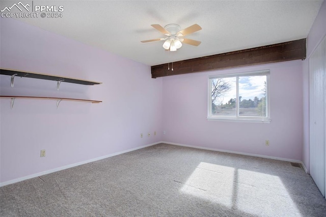 carpeted spare room featuring beamed ceiling and ceiling fan