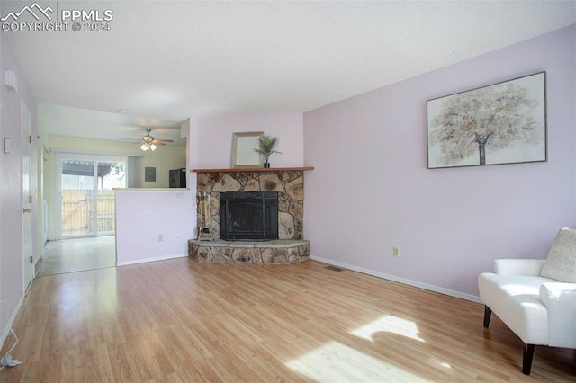 unfurnished living room with a textured ceiling, a fireplace, wood-type flooring, and ceiling fan