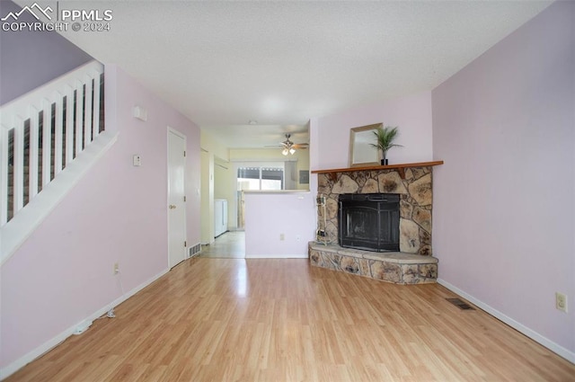 unfurnished living room featuring light hardwood / wood-style flooring, a stone fireplace, and ceiling fan