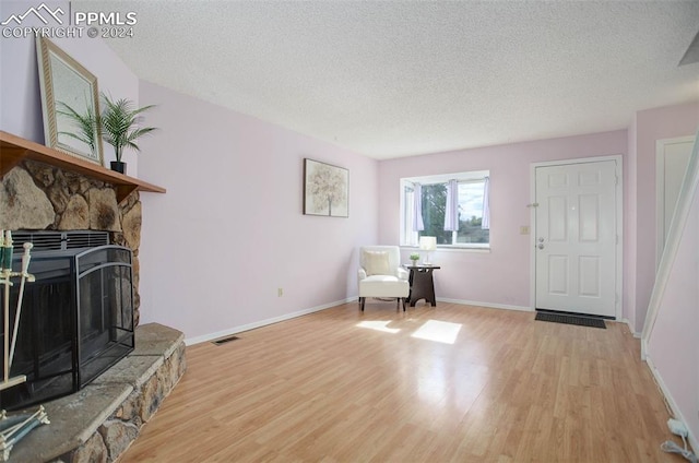 living area featuring light hardwood / wood-style floors, a textured ceiling, and a fireplace