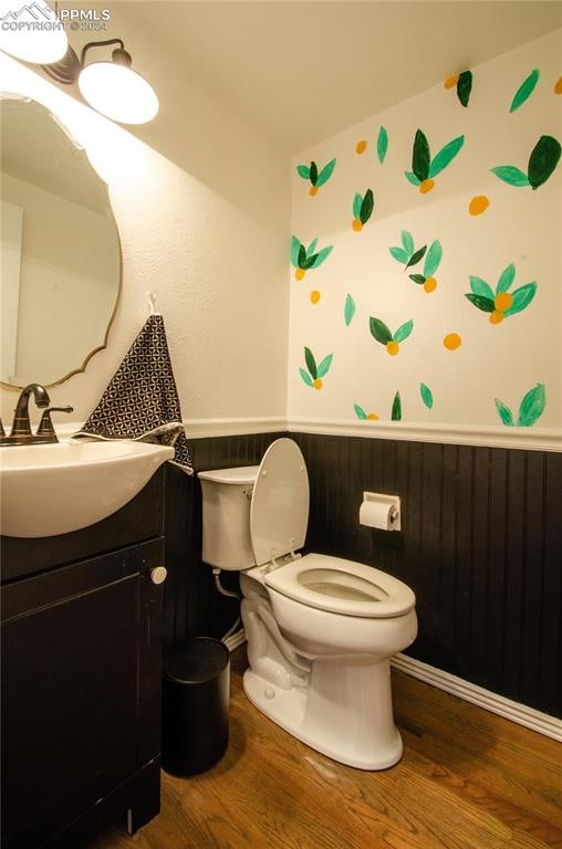 bathroom featuring vanity, toilet, wood-type flooring, and wooden walls